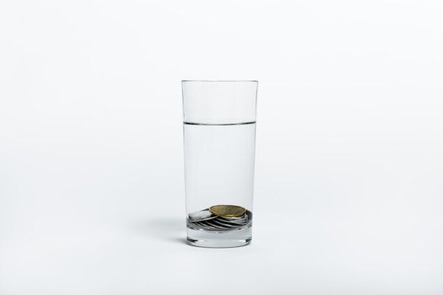 물이 담긴 유리컵 바닥에 동전 몇 개가 가라앉아 있는 모습